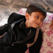 FunnyBones Black Tuxedo with Beaded Giraffe – boy relaxing on a floral sofa