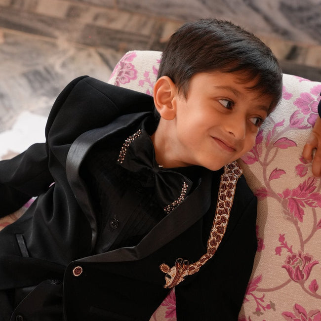 FunnyBones Black Tuxedo with Beaded Giraffe – boy relaxing on a floral sofa