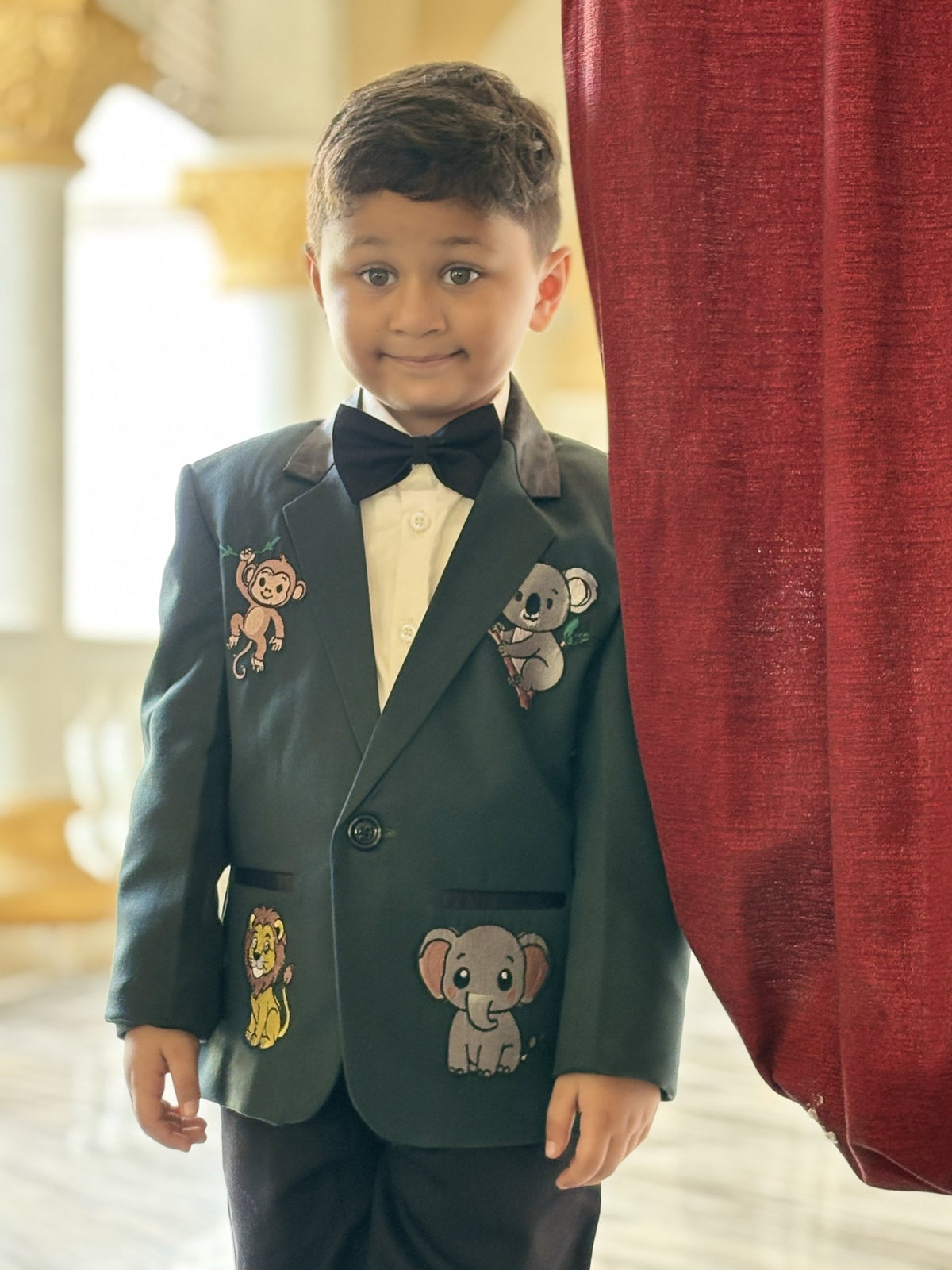 Boy wearing FunnyBones Bottle Green Blazer with Animal Patches – bottle green blazer with embroidered animal patches and bow tie