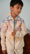 Boy wearing the FunnyBones Mesmerising Colours ivory zipper jacket with pastel blue, pink and peach appliqué and a spread collar, with matching ivory pants