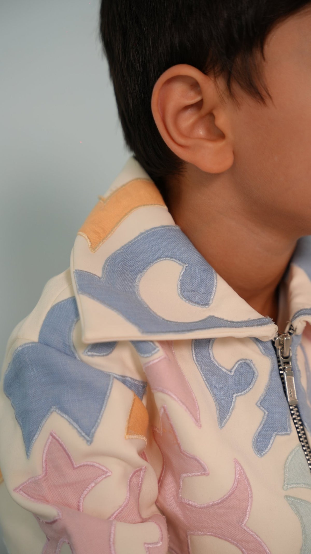 Close-up of the oversized spread collar with powder-blue and peach appliqué and contrast edge stitching